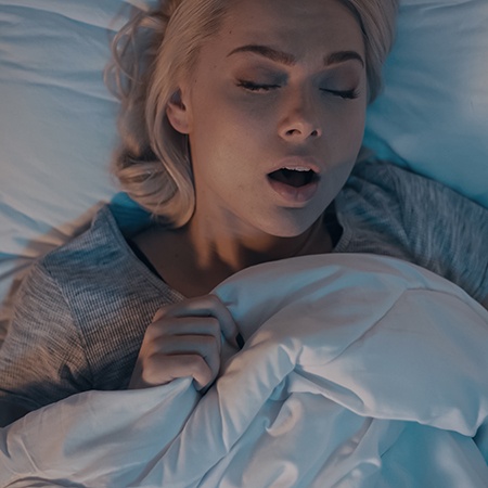 Woman in grey shirt snoring in bed