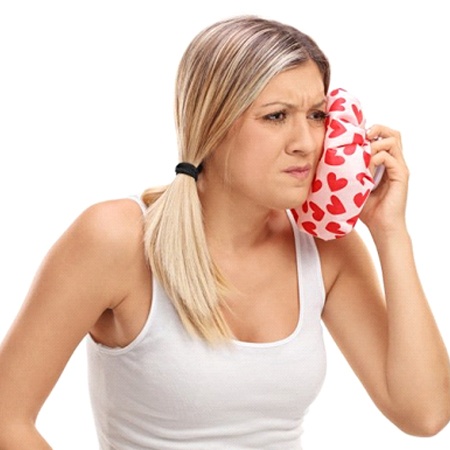 woman applying cold compress to face